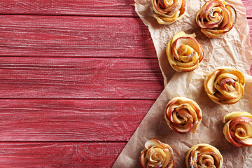 Fresh puff pastry with apple shaped roses on red wooden table