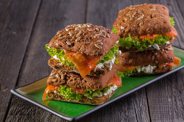 Sandwich with whole grain bread and salmon on rustic wooden back