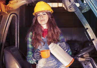 portrait of a worker young girl on coffee break on a forklift
