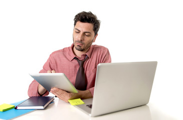 businessman working at office desk using digital tablet pad sitting in front of computer laptop looking busy