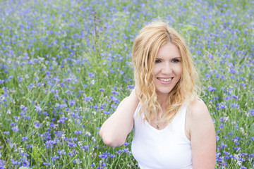 Naklejka na ściany i meble Portrait of young smiling woman on background of cornflowers 