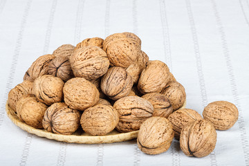 Walnuts in wicker basket on white tablecloth