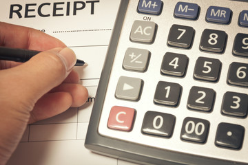 hand someone is writing name on document and calculator on recei