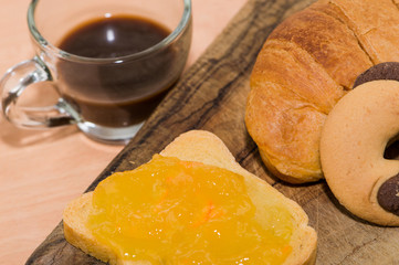 Prima colazione: fetta biscottata con marmellata, cornetto e caffè