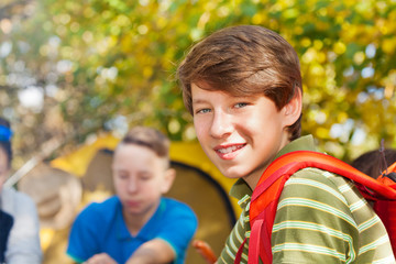 Close-up of boy with rucksack near yellow tent