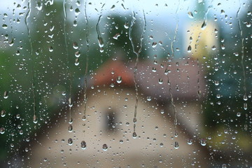 Rain drops on window with house and church in background