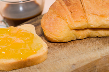 Prima colazione: fetta biscottata con marmellata, cornetto e caffè