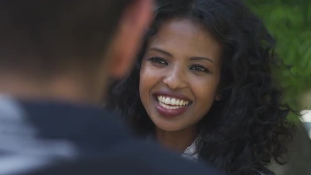 Over the shoulder shot of black woman talking and laughing with male friend