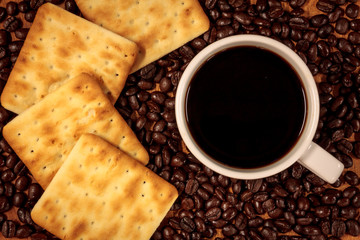 cup of coffee, coffee beans,cracker background.