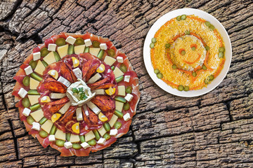 Obraz na płótnie Canvas Plateful of Savory Appetizer Meze, with Bowl of Russian Salad, on Old, Cracked, Stump Cracked Surface.