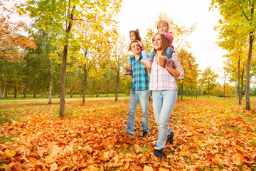 Fototapeta premium Mother and father carry little daughters in park