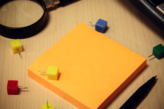black pen,orange paper note,colorful peg,magnifier,base of calcu