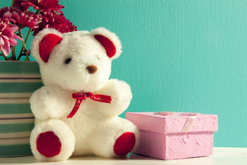 pink gift,teddy bear,flower in vase on green background.