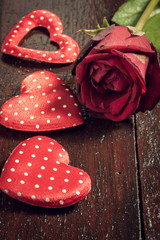 red rose and three heart shape on wood background.