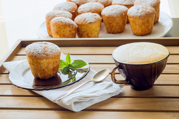 Muffins sprinkled with powdered sugar and cappuccino, daylight