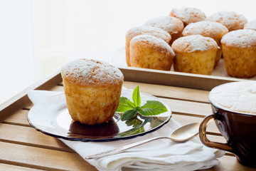 Muffins sprinkled with powdered sugar and cappuccino, daylight