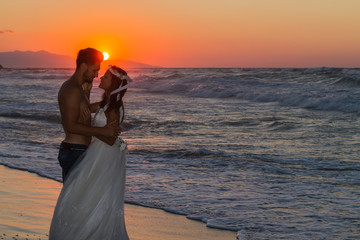 Fototapeta premium Just married young couple on a hazy beach at dusk.