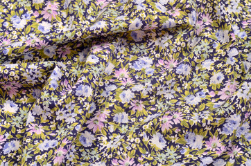 Floral pattern crumpled on fabric. Pink and blue flowers print as background.