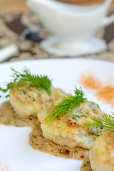 Meatballs served in a dill sauce on a white plate.