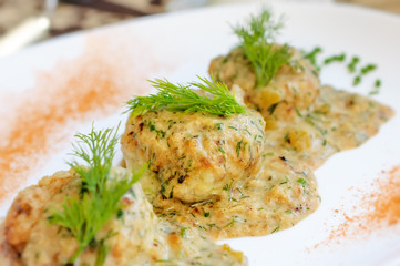 Meatballs served in a dill sauce on a white plate.