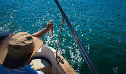 Fisherman in the boat with sea bass in his hand