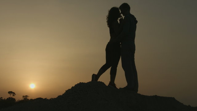 Romantic story of two people in love. Silhouette of couple kissing at sunset