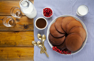 Obraz na płótnie Canvas chocolate pancakes on a wooden table. ripe currants and fresh mi