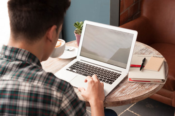 Businessman using laptop with tablet and pen on wooden table in