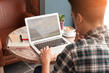 Businessman using laptop with tablet and pen on wooden table in