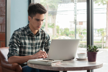 Businessman using laptop with tablet and pen on wooden table in