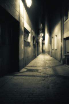 View down a dark, hazy, glowing alleyway at night