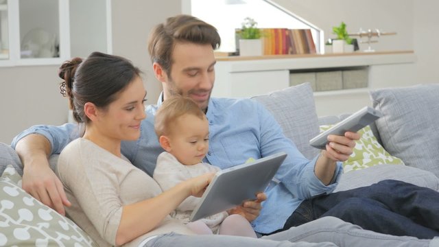 Family with baby in sofa watching tv 