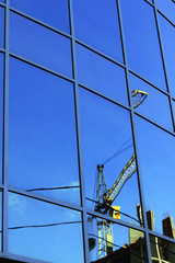reflection of the sky in the glass windows of the crane construction