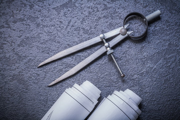 Blueprint rolls pair of compasses on black background maintenanc