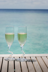 Two champagne glasses by the ocean