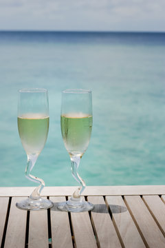 Two champagne glasses by the ocean