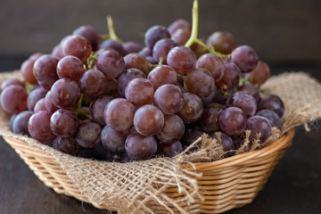 Bunch of grapes in the basket on wooden table