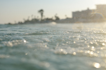 sea wave with foam against tropical holiday resort, soft focus