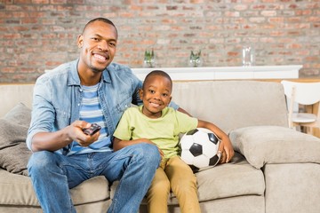 Father and son watching tv together on the couch