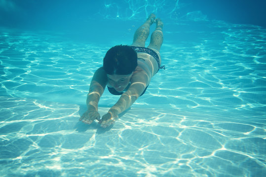 woman swimming underwater in pool, image toned