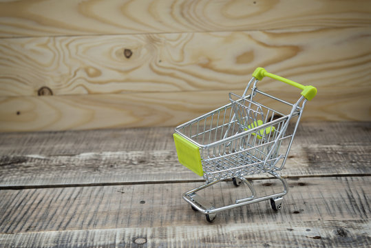 empty mini shopping cart against wooden background
