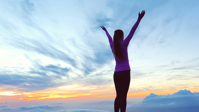 Reaching The Top. Happy successful fitness woman raising arms to the sky at sunset. Success, celebrating goals and achievement.