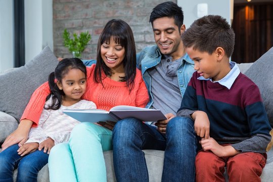 Happy Young Family Reading A Book Together