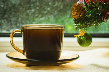 A cup of coffee on the background of Christmas trees and frozen windows