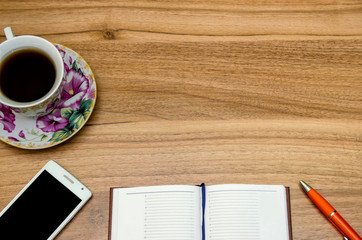 Cup of tea with notepad on wooden background top view