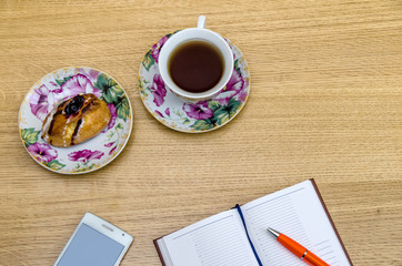 Cup of tea with notepad on wooden background top view
