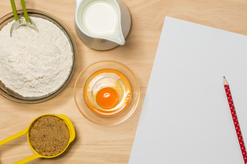 pencil, paper, flour, egg, milk and sugar