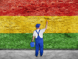 House painter paints Reggae flag on brick wall - 96158747