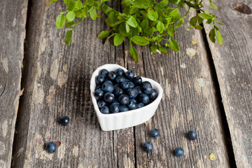 Heart shaped bowl of blueberries on wooden table