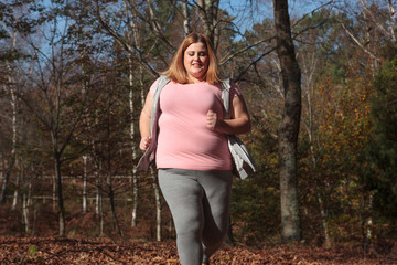 Overweight woman running in a forest